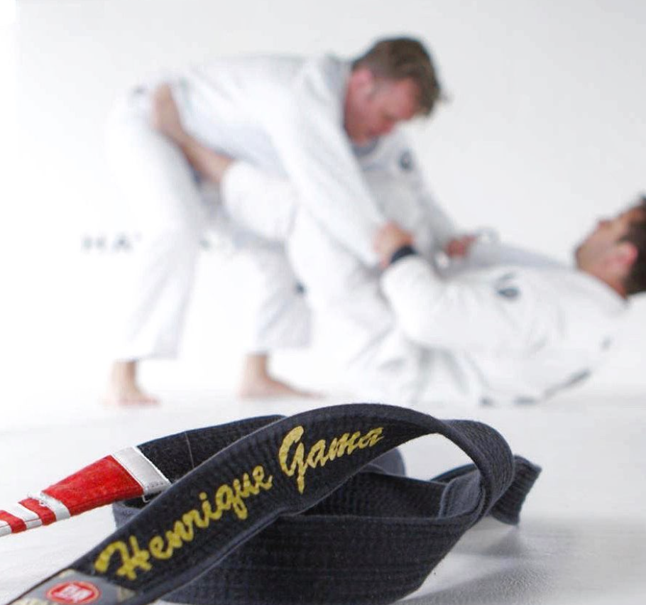 Henrique Gama Filho in his gi on the academy mats beneath the family portraits